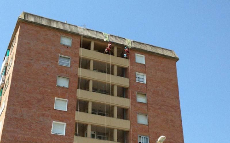 Edificio de varias plantas con trabajadores sujetados con arnés