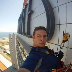 Treballador subjectat amb arnès a façana d'edifici